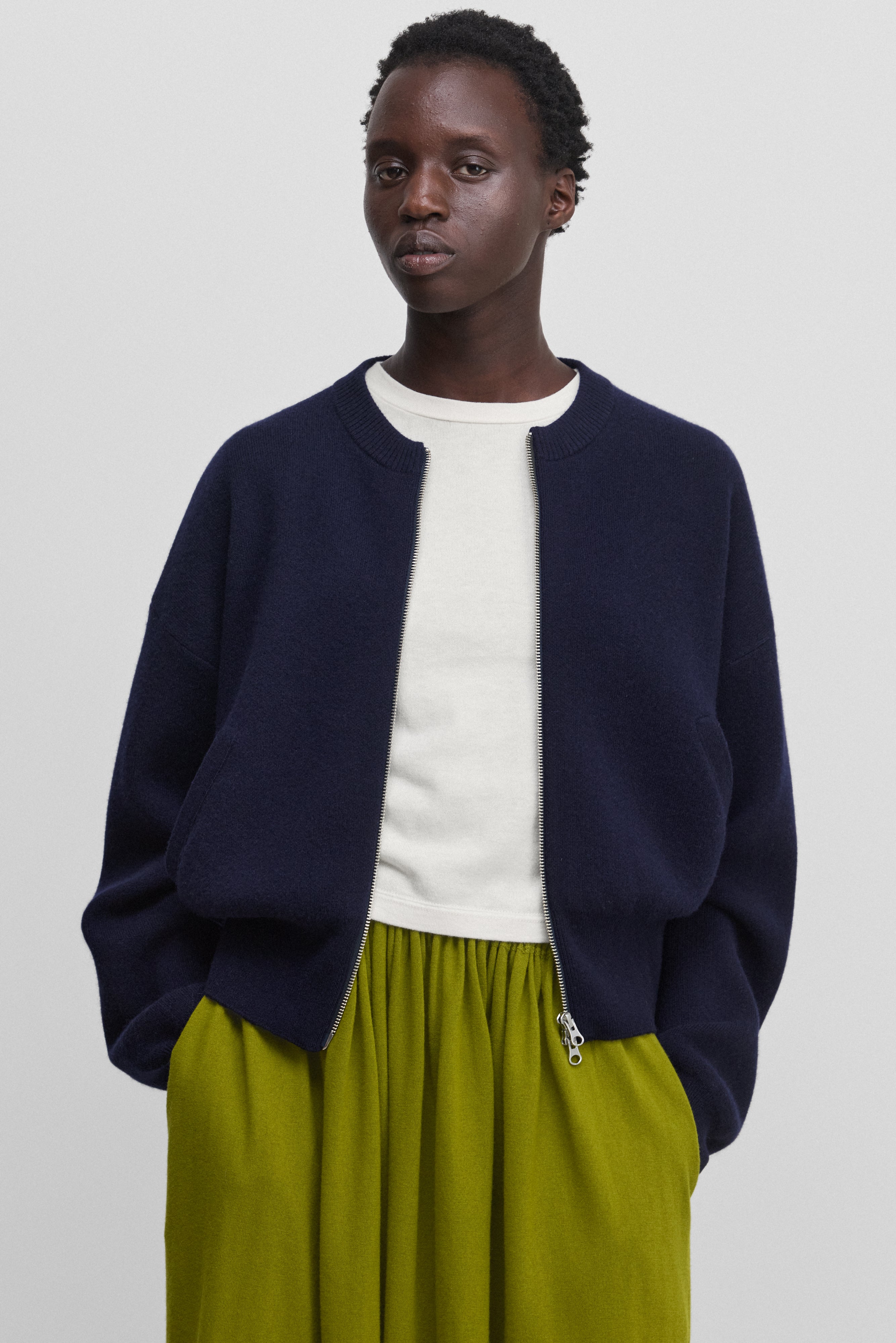 woman wearing a navy blue cashmere zip-up cardigan with crew neck and side pockets.