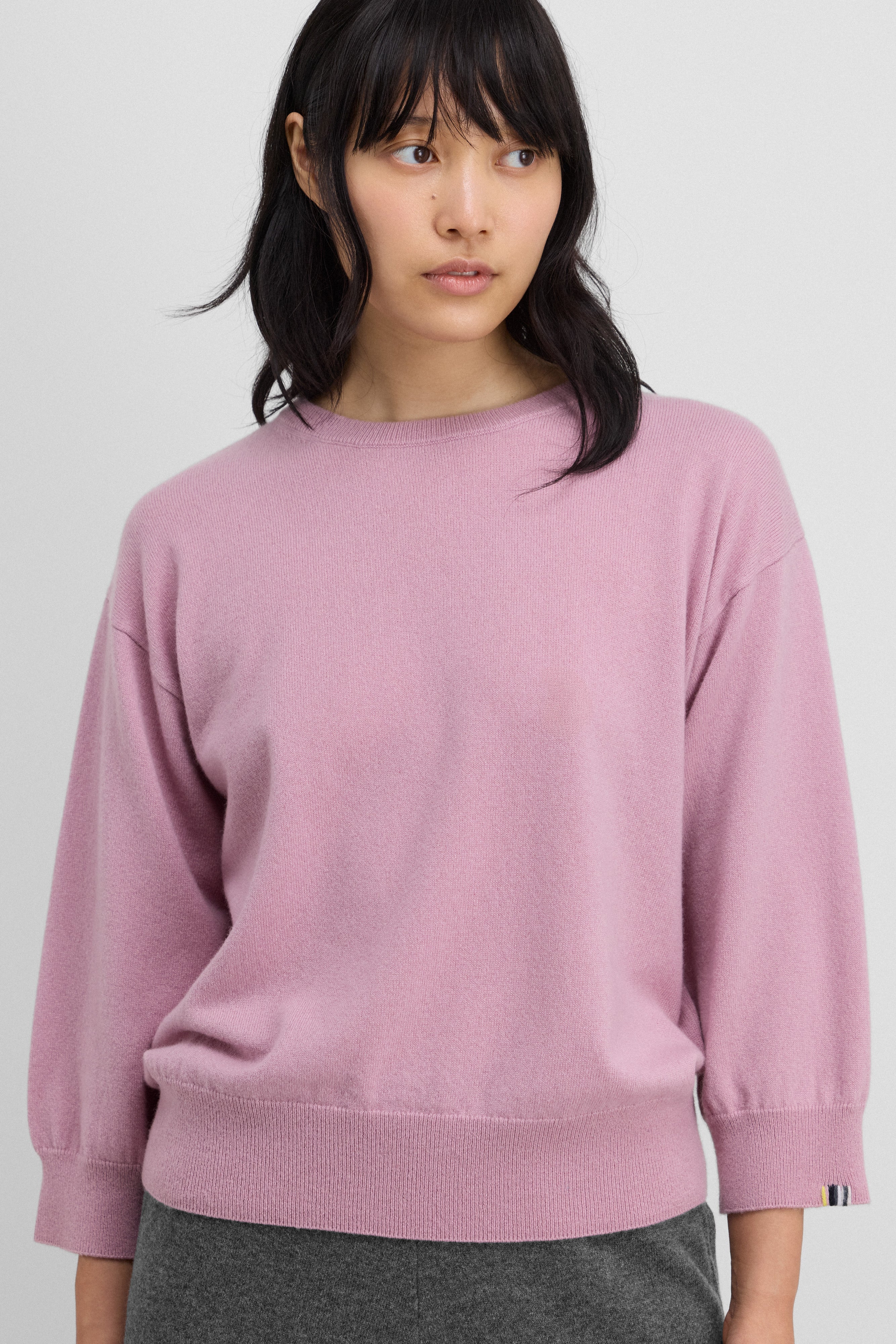 woman wearing a pink 3/4-sleeve cashmere crewneck sweater.