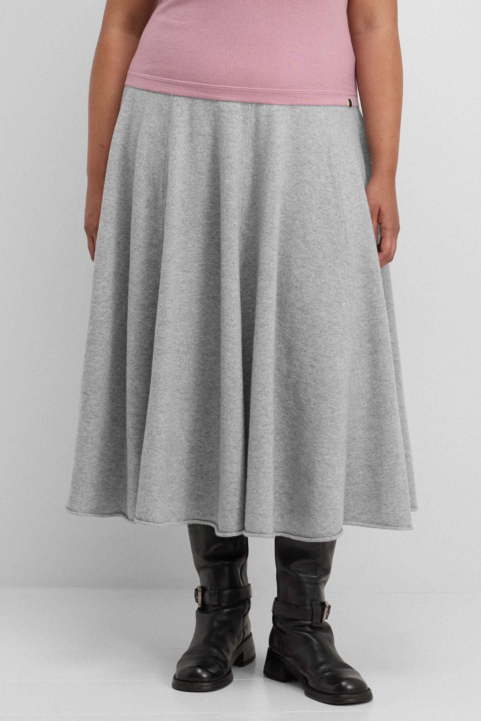 woman wearing a light grey cashmere circle skirt in midi length with ribbed waistband.