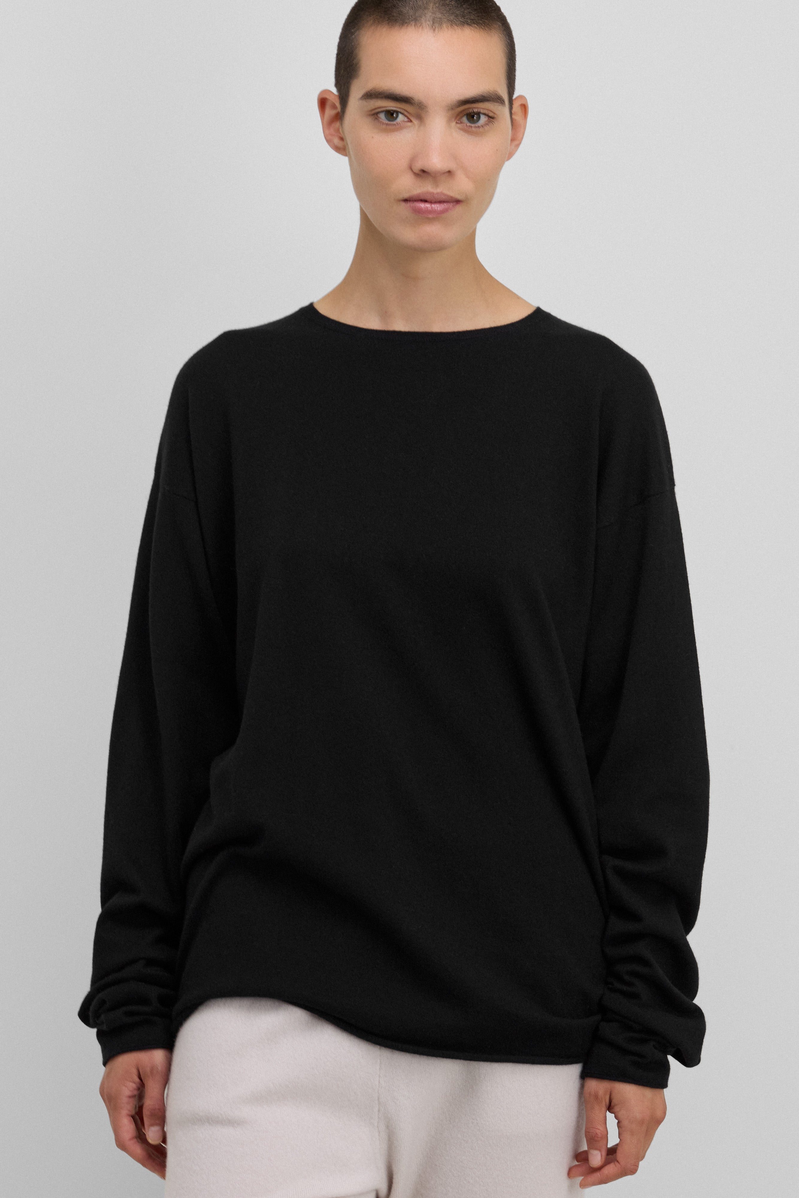 woman wearing an oversized black cotton-cashmere crew-neck top with extra long sleeves.