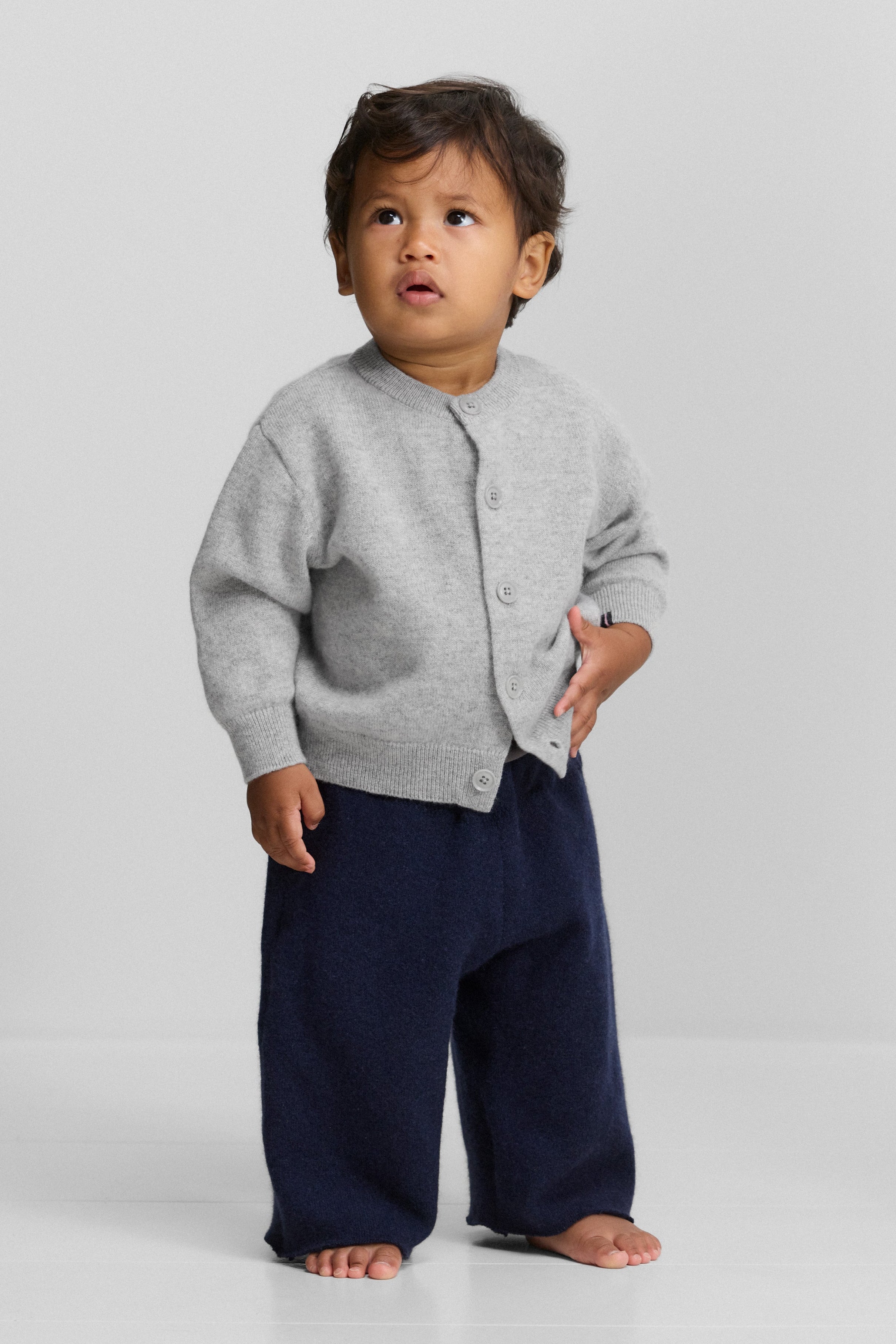 toddler wearing a children’s grey cashmere button up cardigan with a crew-neck and ribbed trims.