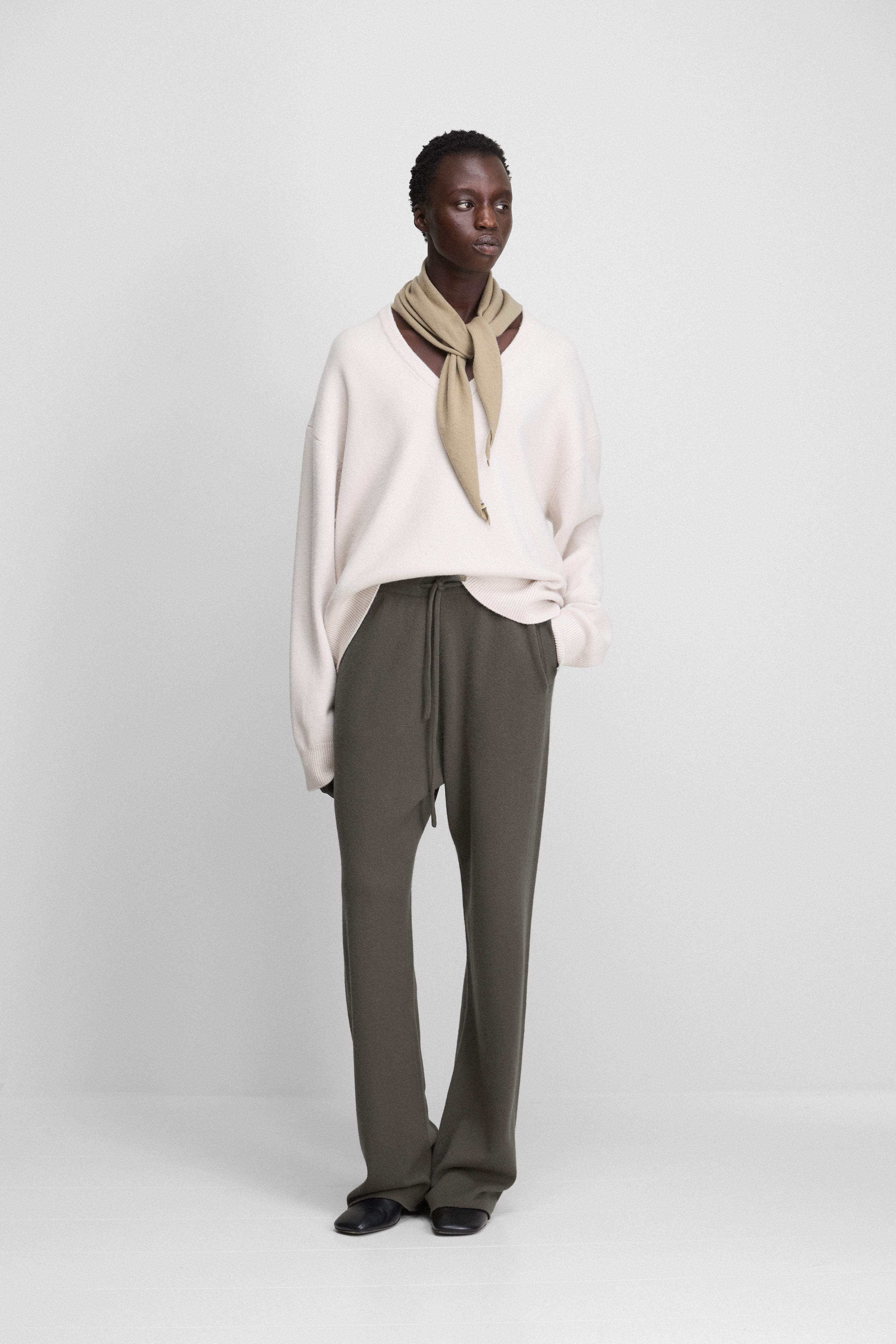 woman wearing a white cashmere v-neck sweater, styled with olive green cashmere pants.