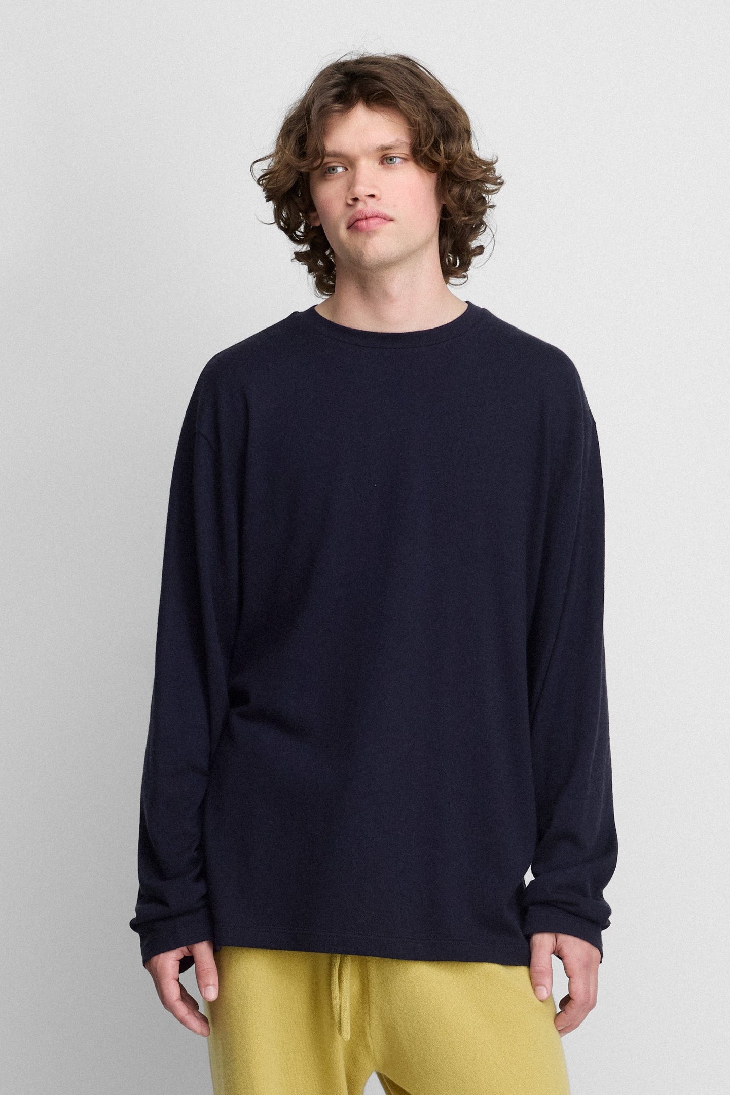 man wearing a navy blue oversized long-sleeved cotton-cashmere t-shirt with a round neckline.