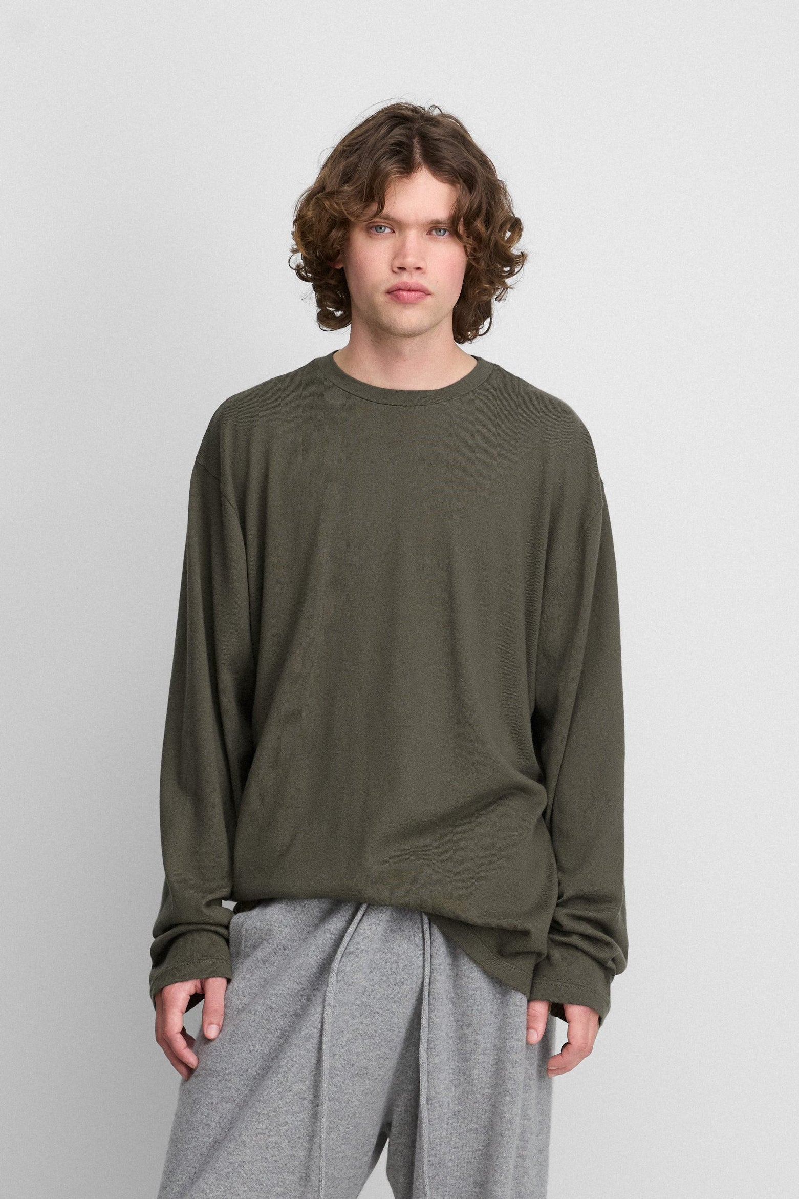 man wearing an army green oversized long-sleeved cotton-cashmere t-shirt with a round neckline and long sleeves.