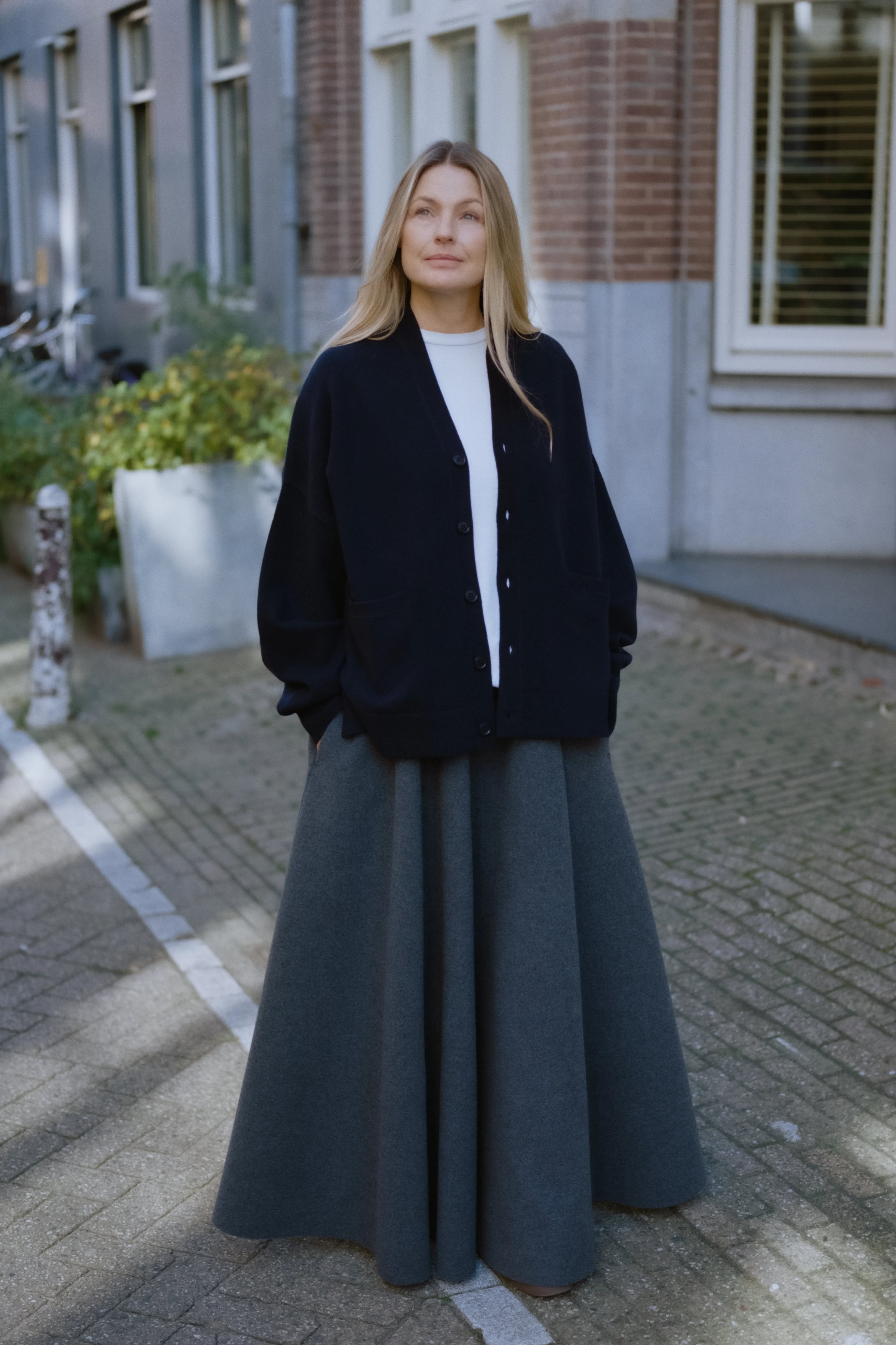 woman wearing an oversized navy blue cashmere v-neck cardigan with five corozo buttons, standing outdoors.